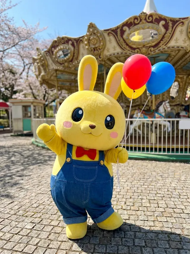 風船を持って手をふる黄色いうさぎのワクピョン